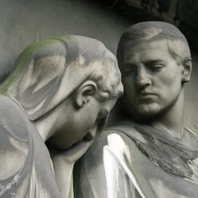Köpfe von Statuen von Mann und Frau aus grauem Stein, traurig nach unten blickend