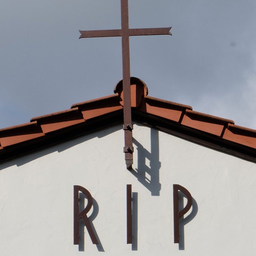 Helle Kapelle mit rotem Dach mit Aufschrift RIP