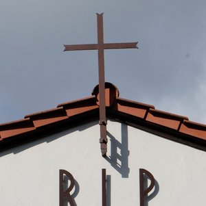 Friedhofskapelle mit Kreuz am Dach und der Aufschrift RIP