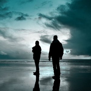 Zwei Menschen stehen bei wolkigem Himmel am Meer