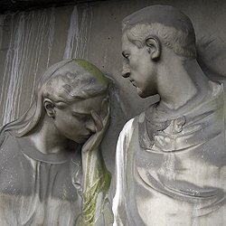 Statuen von Mann und Frau aus grauem Stein, traurig nach unten blickend